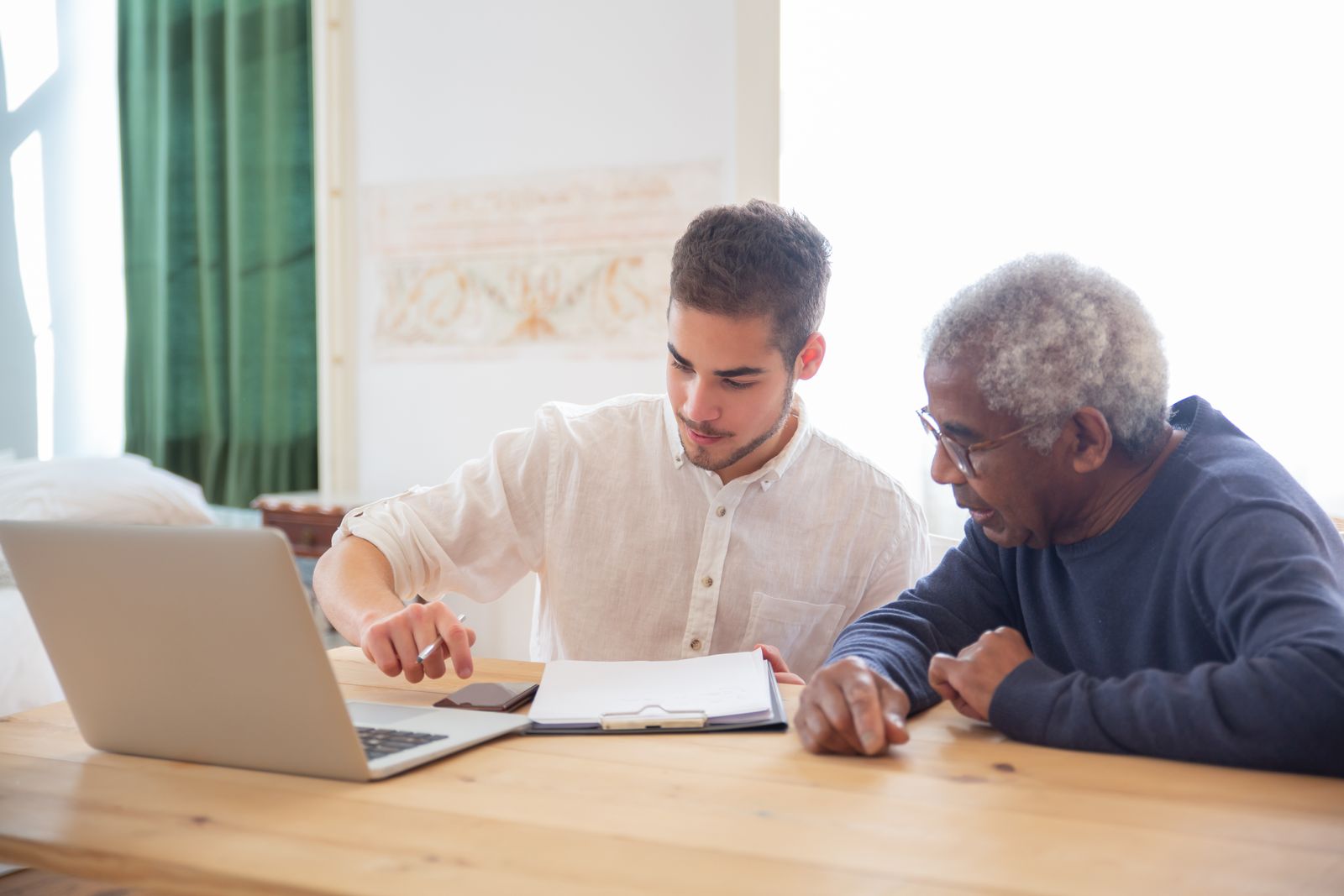 A younger family member and a senior reviewing a plan together at the kitchen table